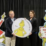 ANA President Tom Uram and ANA Executive Director Kim Kiick hold up large model of the Grinch coin.