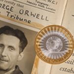 The Royal Mint's George Orwell coin against a newspaper article about George Orwell.