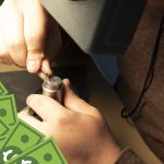 Someone engraving a die with cash in the corner