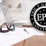 The Eric P. Newman Numismatic Education Society logo next to a laptop, glasses, pens, and paper