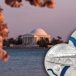 The Tiffany Art Washington, D.C., coin beside the Jefferson Memorial at sunset with cherry blossom trees.