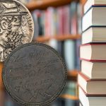 A hobo nickel and an Australian convict love token beside a stack of books.