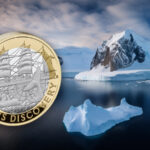 The RRS Discovery commemorative next to an arctic landscape
